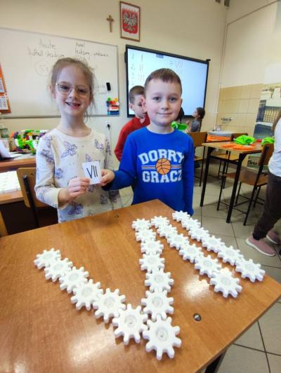 Uczniowie pracujący na klockach Korbo z wykozrystaniem cyfr rzymskich wykorzystanych do budowy planszy zegara