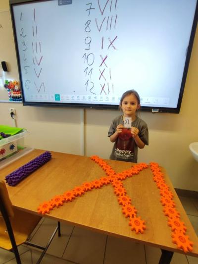 Uczniowie pracujący na klockach Korbo z wykozrystaniem cyfr rzymskich wykorzystanych do budowy planszy zegara