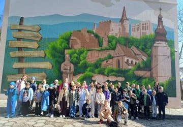 Uczniowie pozują do zdjęcia przed muralem na ścianie kina w Bieczu.