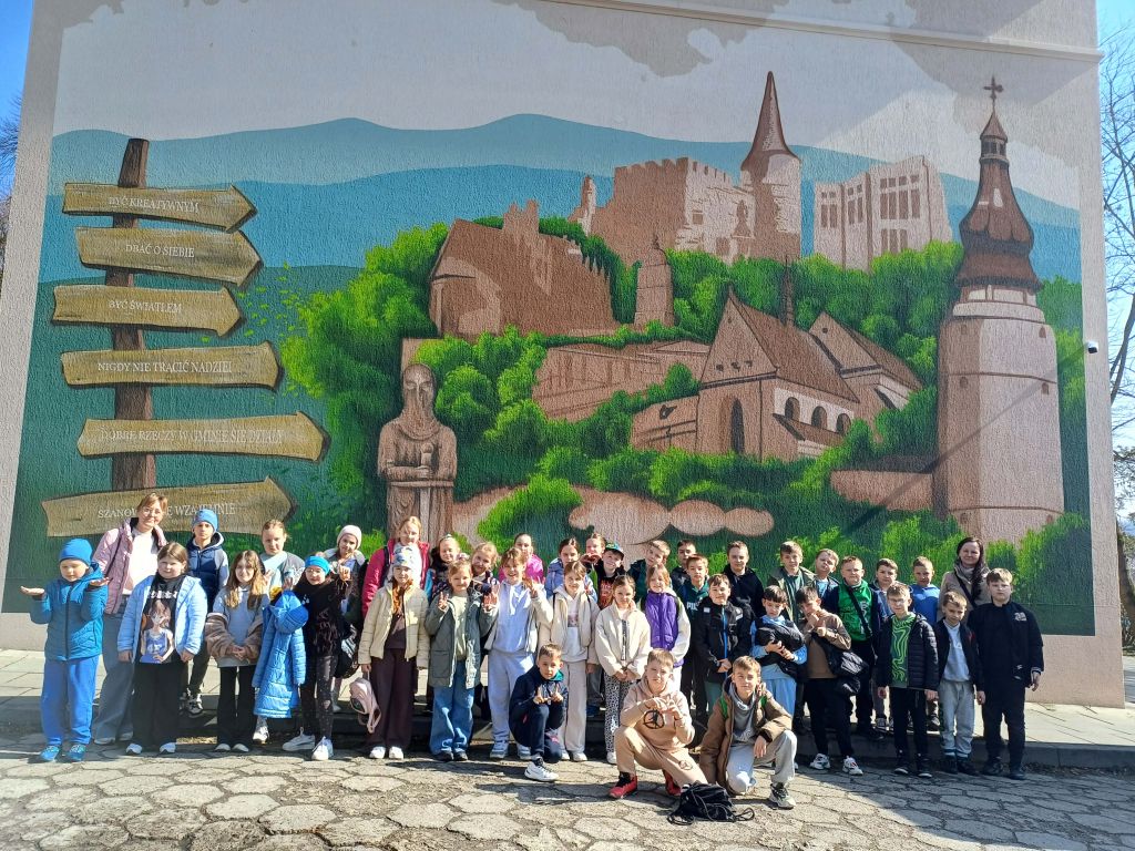 Uczniowie pozują do zdjęcia przed muralem na ścianie kina w Bieczu.