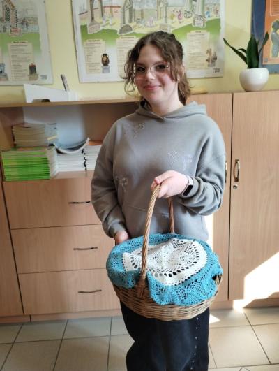 Koszyk wiklinowy przykryty serwetką zamiast plecaka - pomysł dziewczynki z klasy 6b