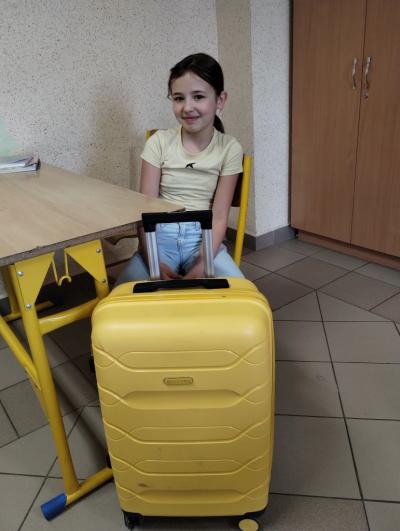 Uczennica klasy 4a z dużą żółtą walizką zamiast plecaka.