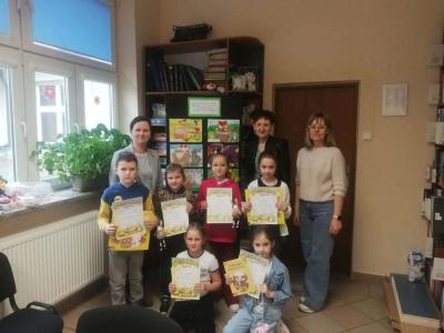 Dzieci z dypolomami w rękach pozują z nauczycielami do zdjęcia