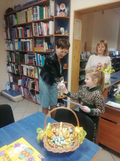 Pani dyrektor wręcza nagrodę dziewczynce w bibliotece szkolnej