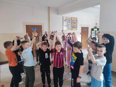 Uczniowie tworzą nić przyjaźni z włóczki.