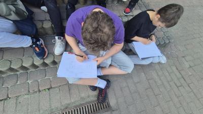 grupa uczniów w skupieniu kreśli kolejne elementy szkicu