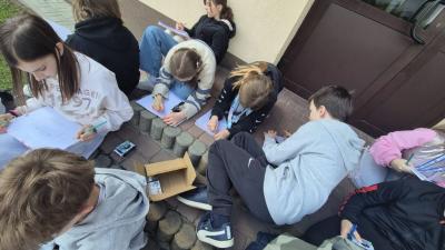 grupa uczniów w skupieniu kreśli kolejne elementy szkicu