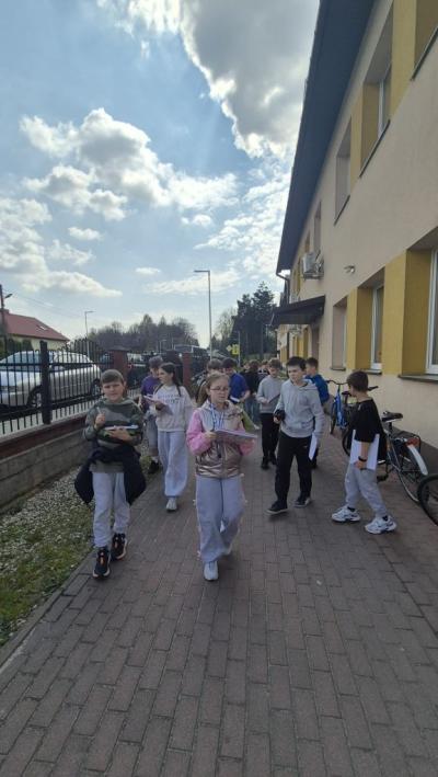 uczniowie idą w stronę hali sportowej i uważnie obserwują teren, komentują