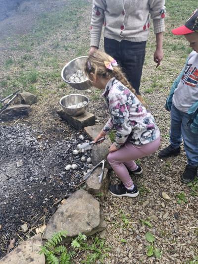 Dziecko wyciąga ziemniaka z ogniska