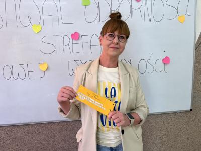 wychowawczyni stoi pod tablicą z uzupełnionym hasłem