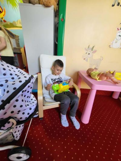 Chłopiec siedzi na fotelu i bawi się zabawką.