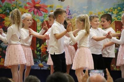Przedszkolaki w kolorowych strojach występują na scenie z okazji Święta Rodziny