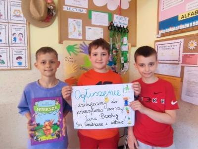 Trzech chłopców pozuje do zdjęcia z plakatem