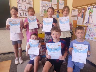 Uczniowie pozują do zdjęcia z dyplomam