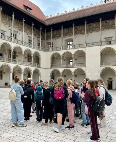 uczniowie stoją z przewodnikiem na Dziedzińcu Arkadowym