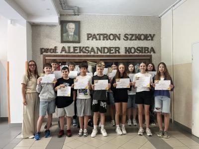 klasa 6b trzyma dyplomy za projekt etwinning, obok stoi nauczzycielka