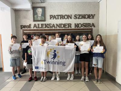 uczniowie trzymają dyplomy i flagę etwinning