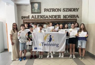 zdjęcie uczniów klasy 6b wraz z nauczycielką , uczniowie trzymają dyplomy i flagę etwinning