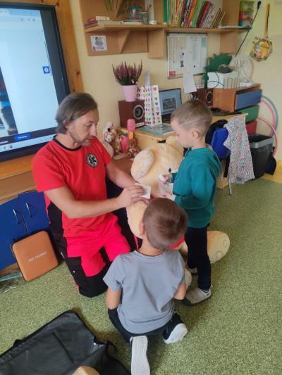 Dwóch chłopców z pomocą ratownika bandażuje łapkę miasia