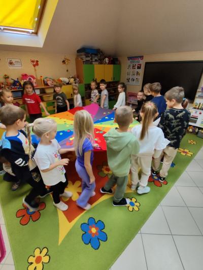 Dzieci kręcą chustą animacyjną, na której leżą sylwety jabłek