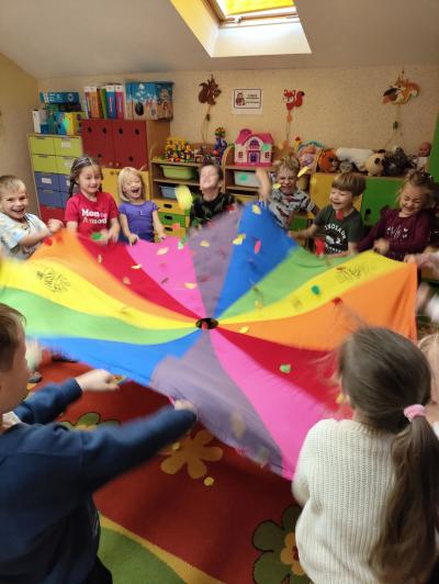 Dzieci wachlują chustą i strącają z niej sylwety jabłek