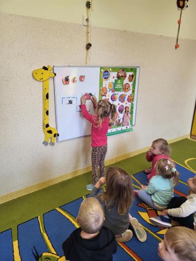 Dziewczynka układa jabłko z 3 części.