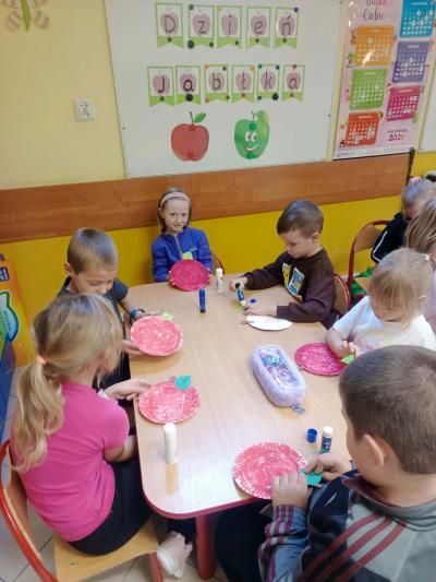 Dzieci doklejają do jabłek listki i ogonki.