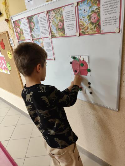 Chłopiec układa puzzle w kształt czerwonego jabłka