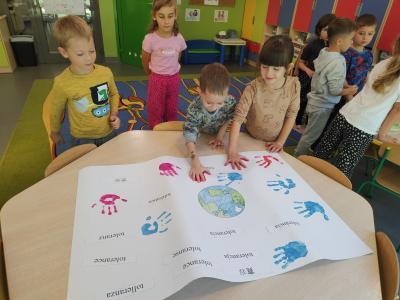 Dziewczynka i chłopiec odbijają ręce na plakacie.