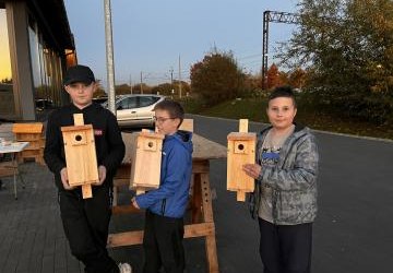 trzech chłopców trzyma budki lęgowe