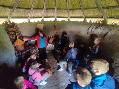 Wizyta w Globalnych Wioskach Świata. Dzieci oglądają jak wygląda afrykańska chatka w środku wraz z wyposażeniem.