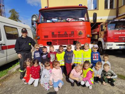 Wspólne zdjęcie dzieci z grupy Biedronki z panem strażakiem. W tle wóz strażacki.