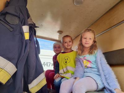 Trzy dziewczynki z grupy Pszczółki siedzą w wozie strażackim