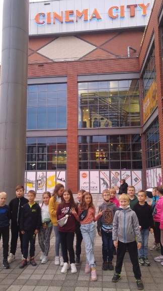 Grupa dzieci stoi przed budynkiem z napisem Cinema City