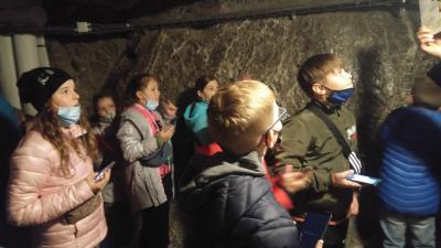 Dzieci z zainteresowaniem słuchają opowieści przewodnika o kopalni soli