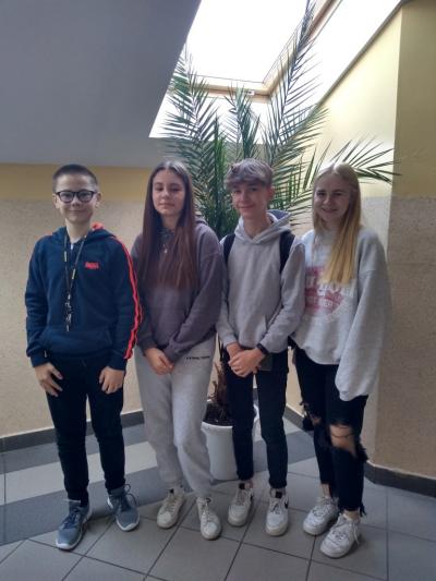 2 uczniów i 2 uczennice z klasy 8 i 7 zakwalifikowani do etapu rejonowego Małopolskiego Konkursu z Języka Angielskiego stoją na korytarzu szkolnym