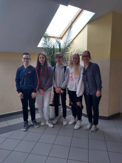 nauczycielka, 2 uczniów i  2 uczennice z klasy 8b i 7b zakwalifikowani do etapu rejonowego Małopolskiego Konkursu z Języka Angielskiego stoją na korytarzu szkolnym