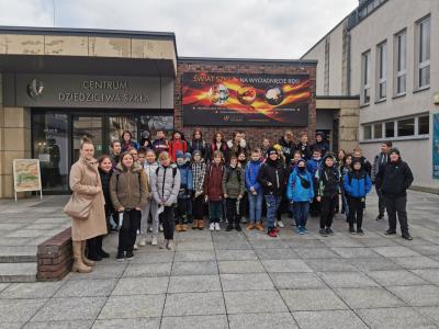 Grupa uczniów stoi na tle budynku ,,Centrum Dziedzictwa Szkła” w Krośnie