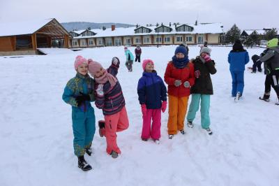Dzieci bawią się śniegiem. W tle snieżna aura.