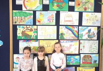 dziewczynki reprezentujące nasze przedszkole, w tle wystaw prac plastycznych