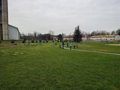 Uczniowie sprzątaja boisko piłkarskie ze śmieci.