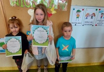 Trójka dzieci zajmująca kolejno 1, 2 i 3 miejsce z nagrodami i dyplomami