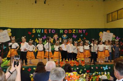 Przedszkolaki z grupy Misie występują na scenie - w tle napis święto rodziny. Przed sceną pięknie udekorowane kwiaty w doniczkach.