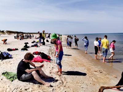 Dzieci wraz z opiekunami odpoczywają nad brzegiem morza po wyczerpującej, siedmiokilometrowej wędrówce w Słowińskim Parku Narodowym.