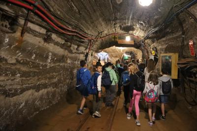 Dzieci maszerują kopalnianym korytarzem. Ściany wykonane z drewnianych beli.