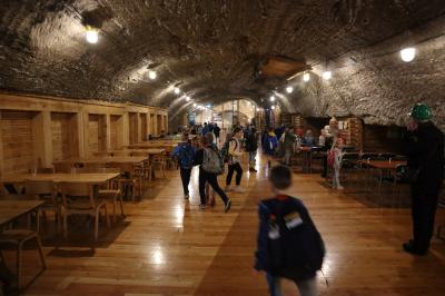 Dzieci zwiedzają w kopalni soli część wypoczynkową - duże wysokie wydrążone groty. Na ziemi podłoga z drewna.