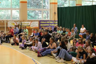 Uczniami z Zespołu Szkolno - Przedszkolnego w Libuszy uczestniczą w spotkaniu z Marcinem Prusem. Uczniowie siedzą  skierowanie w stronę prowadzącego spotkanie.