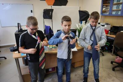 konkurencja umiejętności - trzech chłopców wiąże krawat na swojej szui.