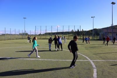 Uczniowie na boisku grają w piłkę nożną. Gra odbywa się na orliku.
