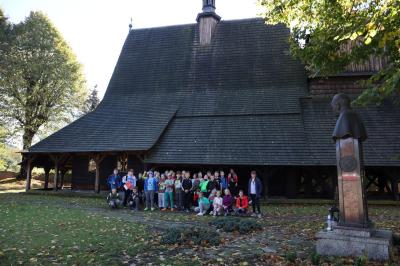 Uczniowie pozują do zdjęcia grupowego - w tle drewniany kościół.